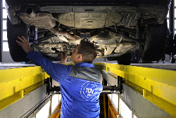 TÜV Prüfer untersucht den Unterboden eines Fahrzeugs